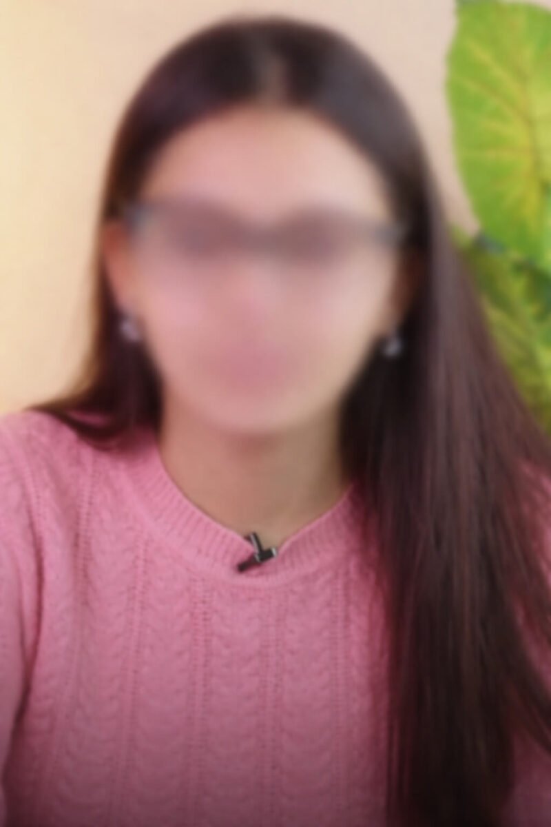 Blurred face portrait of a woman wearing glasses and a pink sweater for privacy protection example