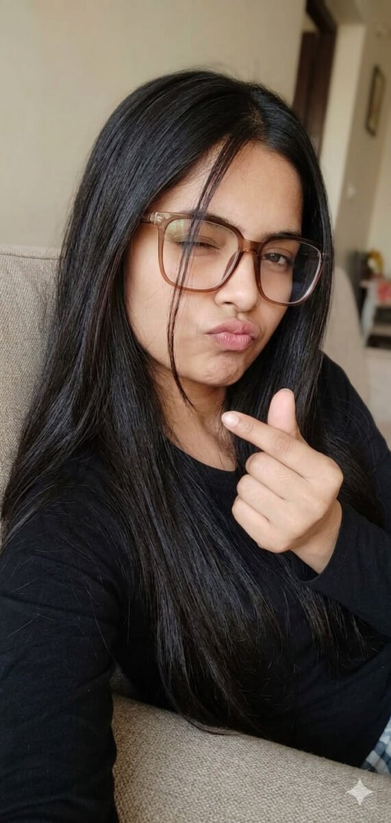 Cute selfie style portrait of a girl with long hair wearing glasses and making finger heart sign